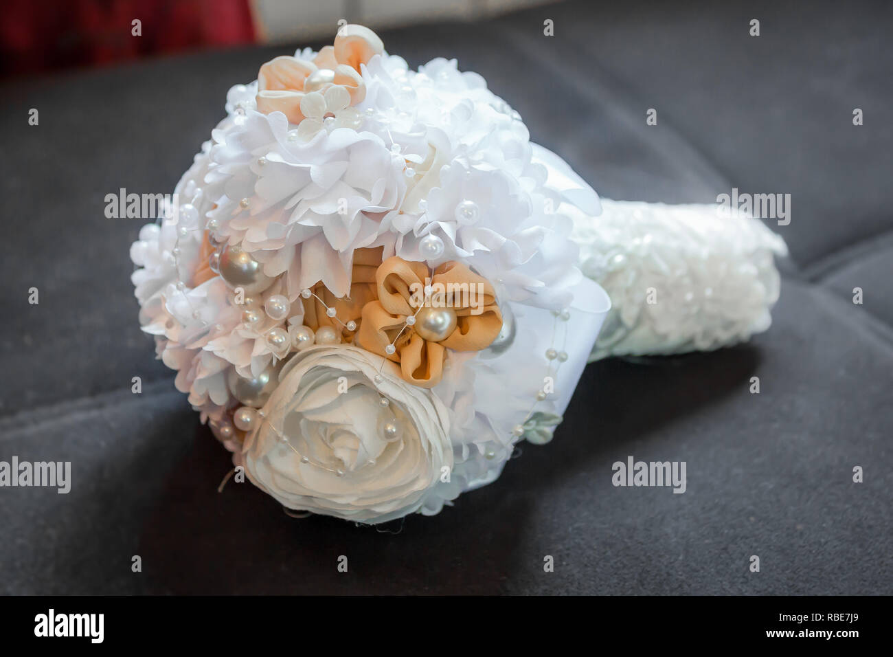 Bouquet nozze di bianco e arancione artificiale fiori in tessuto decorato con perle. Close up. Foto Stock