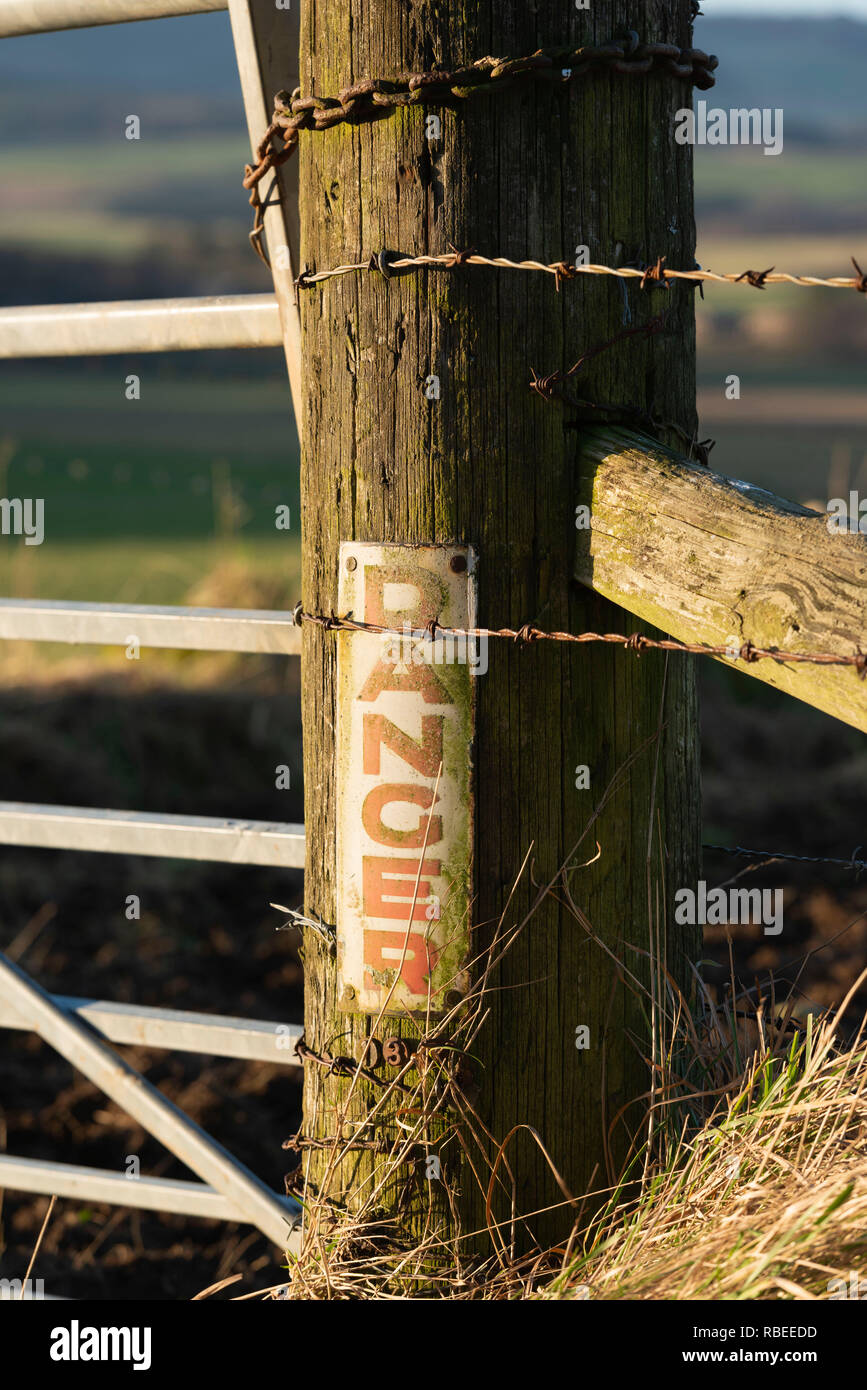 Un vecchio palo telefonico (o palo elettrico) che mostra ancora un 'DIRA' segno di avvertimento è stata riciclata come una Fattoria Post in Rural Aberdeenshire. Foto Stock