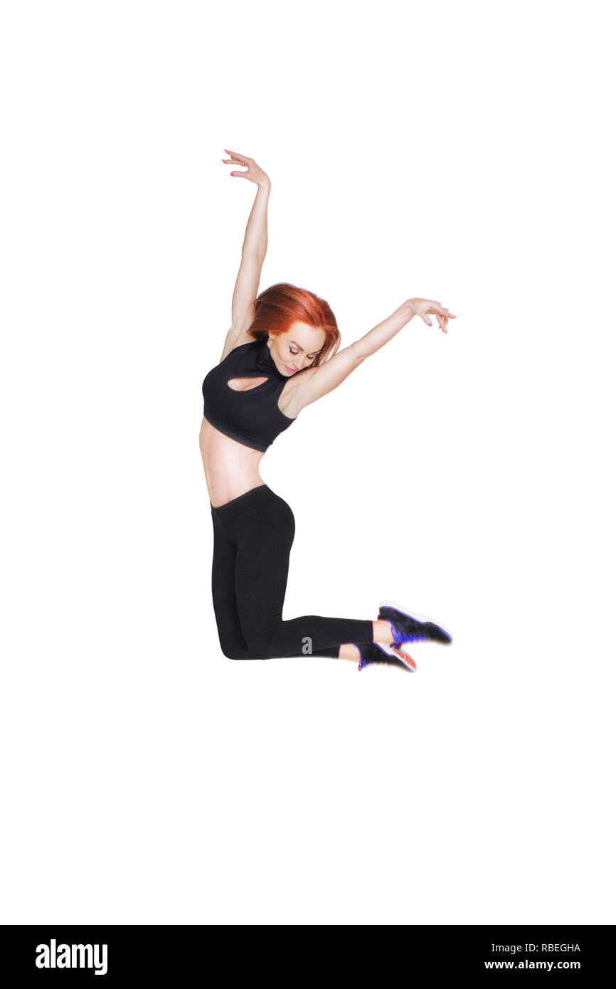 Athletic ragazza con i capelli rossi sorridente in un salto su sfondo bianco Foto Stock