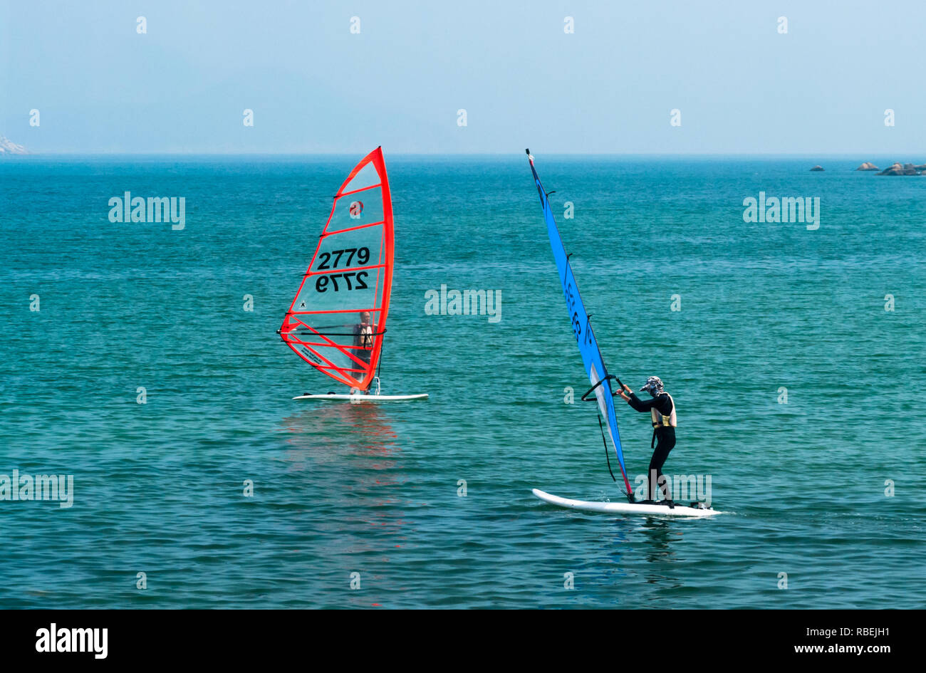 Due surfisti del vento favorevole di cattura le correnti di aria come loro velocità lungo l'acqua nell'oceano blu acque al largo di Hong Kong, Cina, in settembre. Foto Stock
