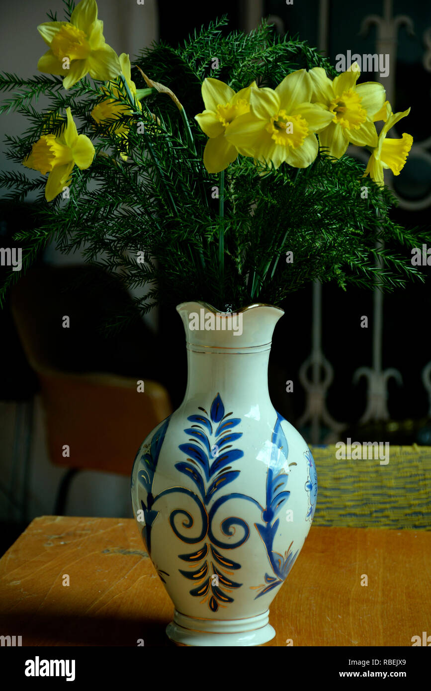 Un mazzo di narcisi di diverse varietà. Fiori in un vaso e la coppa sul tavolo. Retrò ancora in vita. Narciso Foto Stock