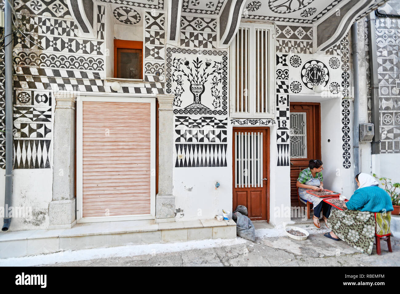 Donne locali opera al di fuori di una casa tradizionale con il famoso geometrico modelli scratch nel borgo medievale di Pyrgi sull isola di Chios, Grecia Foto Stock