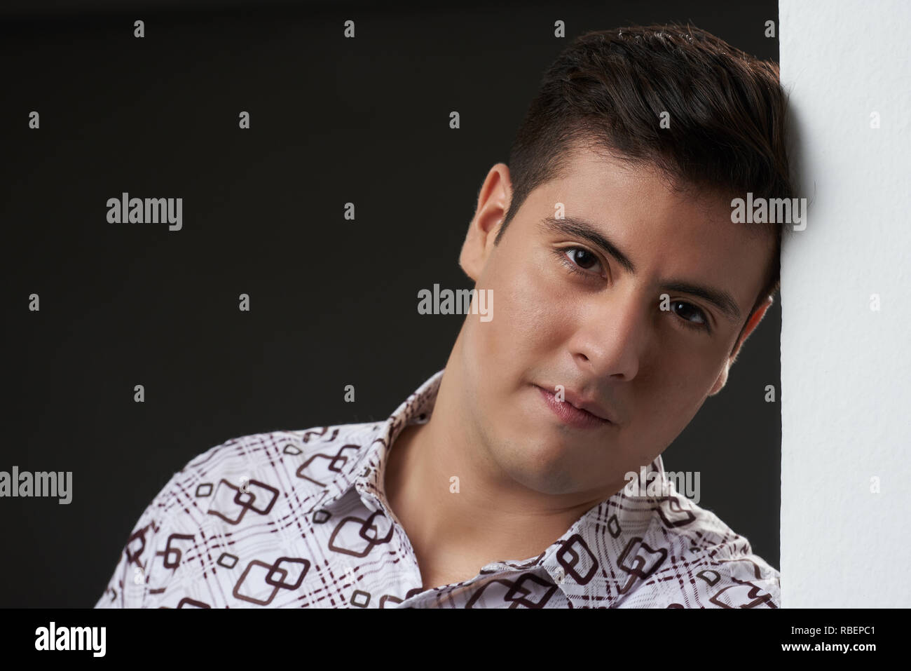 Giovane uomo appoggiato sulla parete. Ritratto di seriuos uomo latino close up Foto Stock