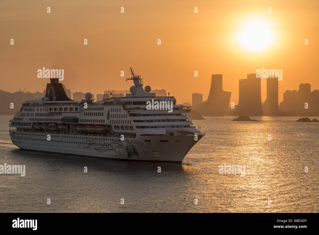 Moderna nave da crociera avvicinando Xiamen al tramonto Foto Stock