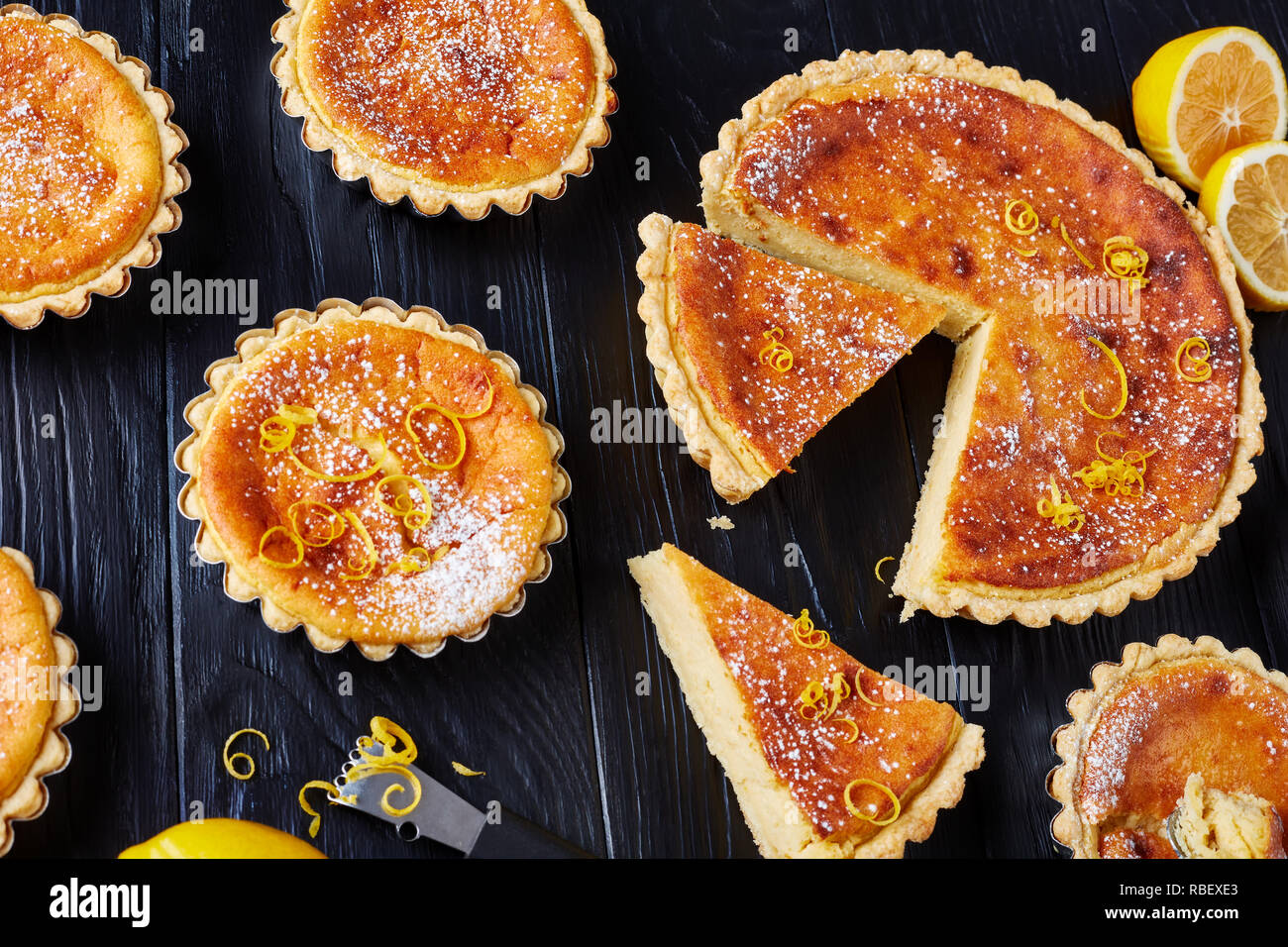 Pasqua svizzera dessert - crostate di semola spolverati con zucchero a velo e la scorza di limone, gateau de Paques, Osterfladen, su una tavola nera con limone, horizo Foto Stock