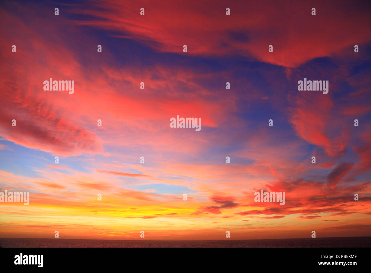 Drammatico, brillante, rosso, arancione, rosa, blu cielo, cieli, dopo il tramonto, cloud, nuvole, formazione, multi colore, colori Foto Stock