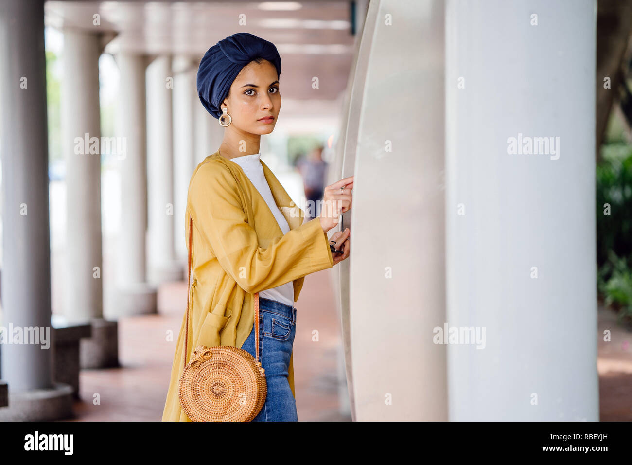 Un giovane musulmano donna asiatica del Medio Oriente in discesa un elegante vestito alla moda e un turban (hijab) consulta una mappa per prendere il bus. Foto Stock