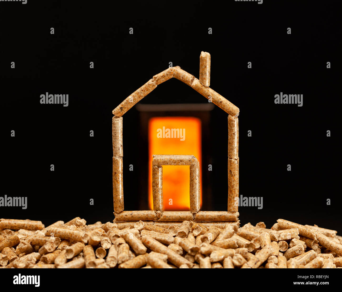 Casa in miniatura fatta con pellet di legno. Concetto di riscaldamento con camera di combustione in background. Foto Stock