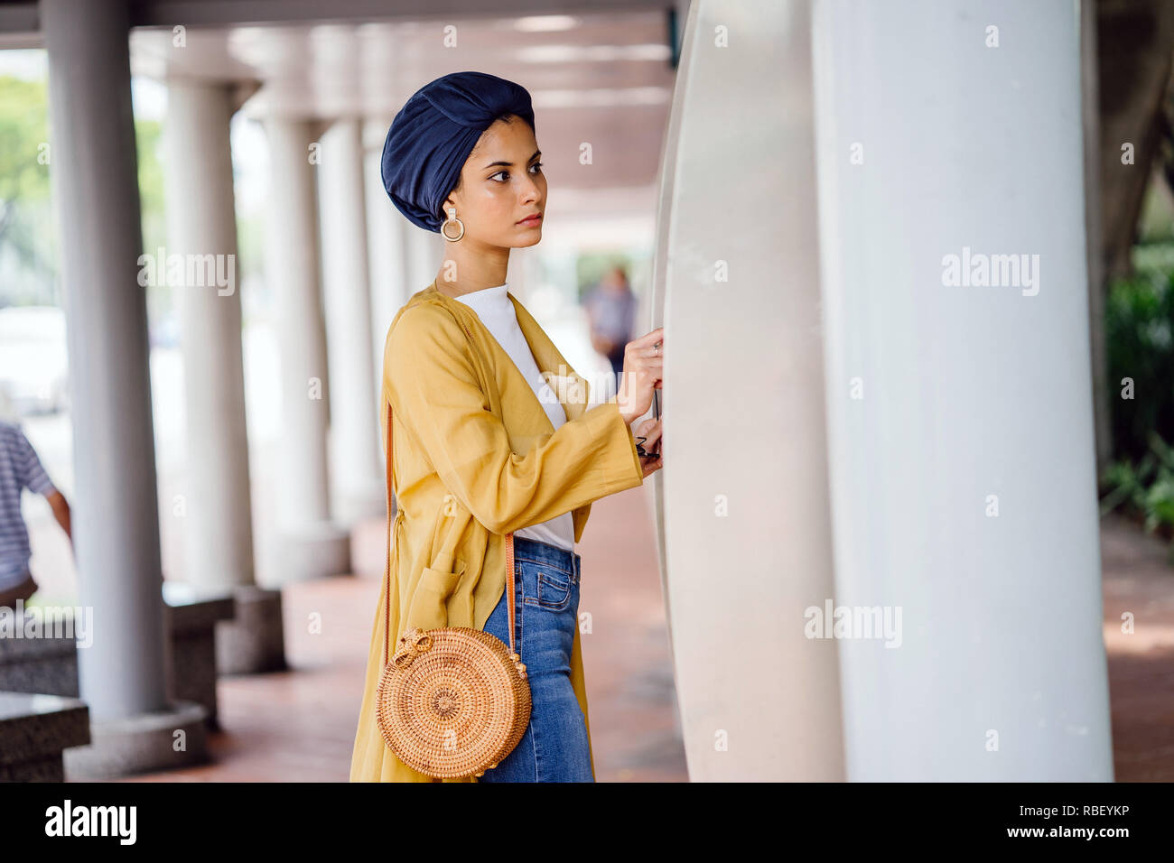 Un giovane musulmano donna asiatica del Medio Oriente in discesa un elegante vestito alla moda e un turban (hijab) consulta una mappa per prendere il bus. Foto Stock