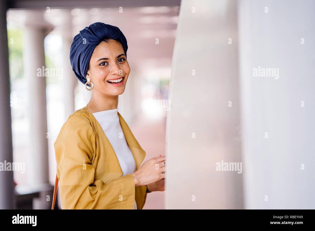 Un giovane musulmano donna asiatica del Medio Oriente in discesa un elegante vestito alla moda e un turban (hijab) consulta una mappa per prendere il bus. Foto Stock