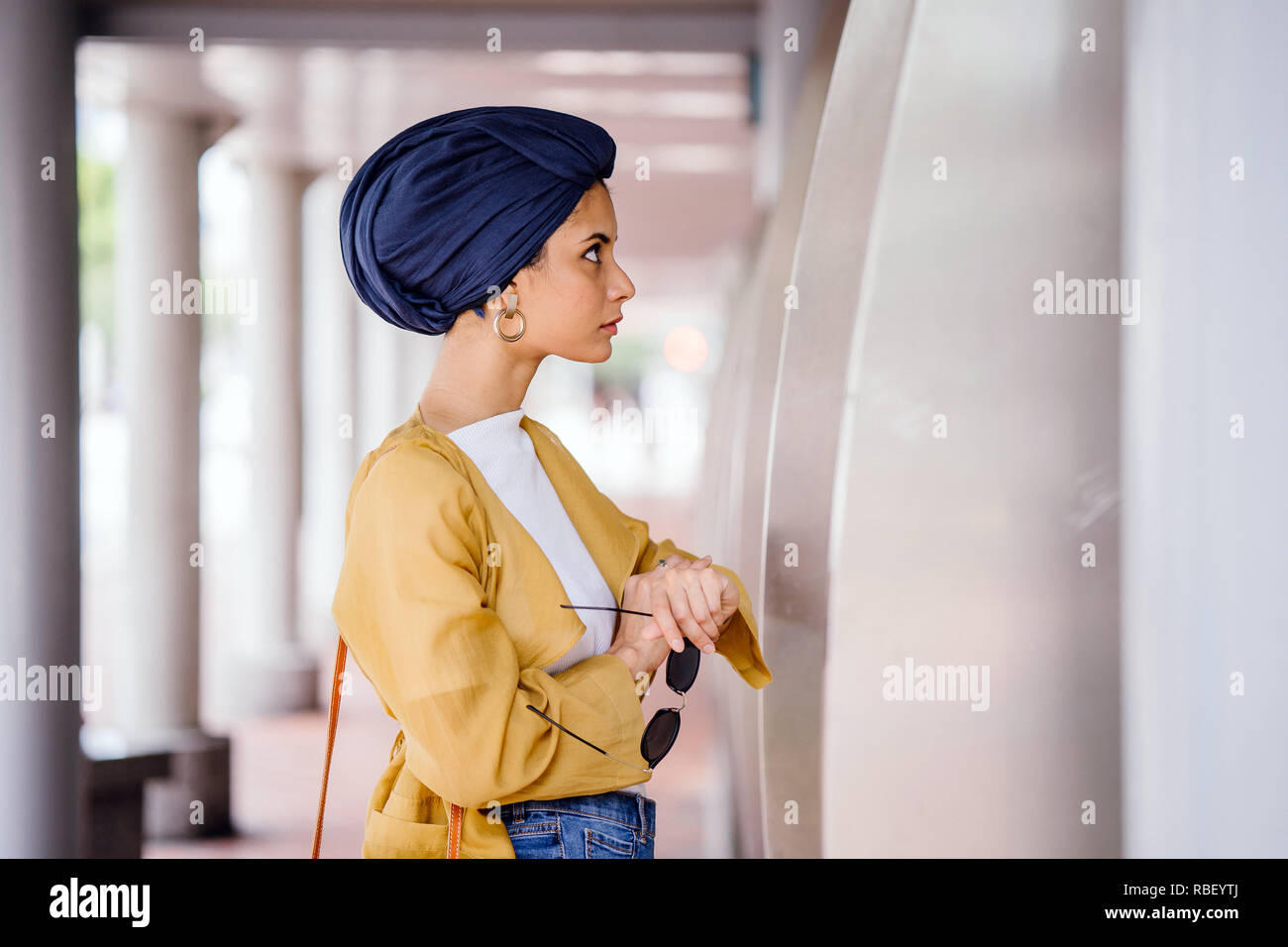 Un giovane musulmano donna asiatica del Medio Oriente in discesa un elegante vestito alla moda e un turban (hijab) consulta una mappa per prendere il bus. Foto Stock