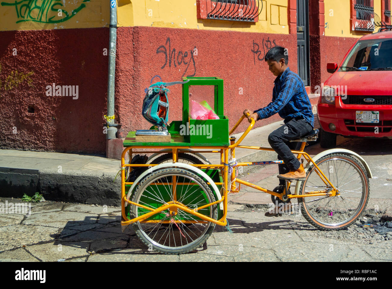 Ragazzo locale lavorando su una bicicletta in strada, San Cristobal de las Casas, Chiapas, Messico Foto Stock