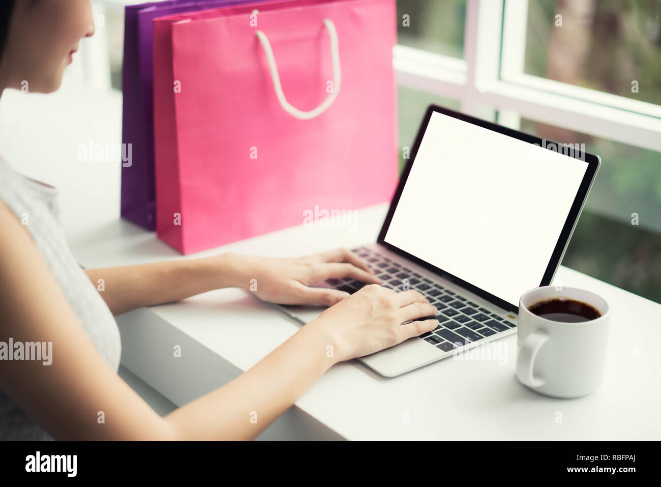 Gli acquirenti asiatici donna con le borse della spesa di acquisto on-line e la scelta dei prodotti presso il sito Web di shopping in un negozio di caffè. Foto Stock