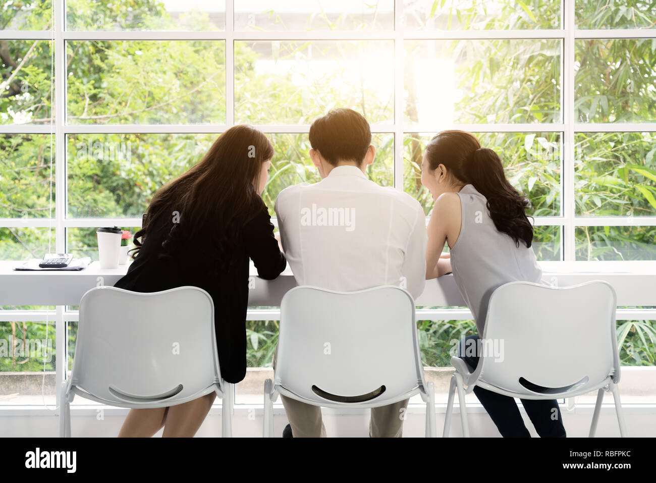Un gruppo di tre giovani asiatici business persone riunite insieme a un tavolo per discutere un'idea interessante nella caffetteria. Foto Stock