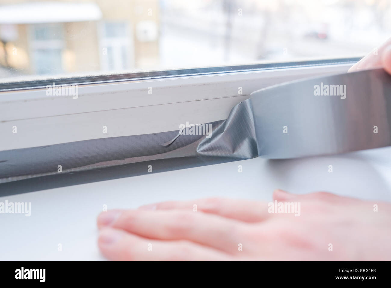 Lavoratore di mettere il nastro di tenuta sulla finestra in casa Foto Stock