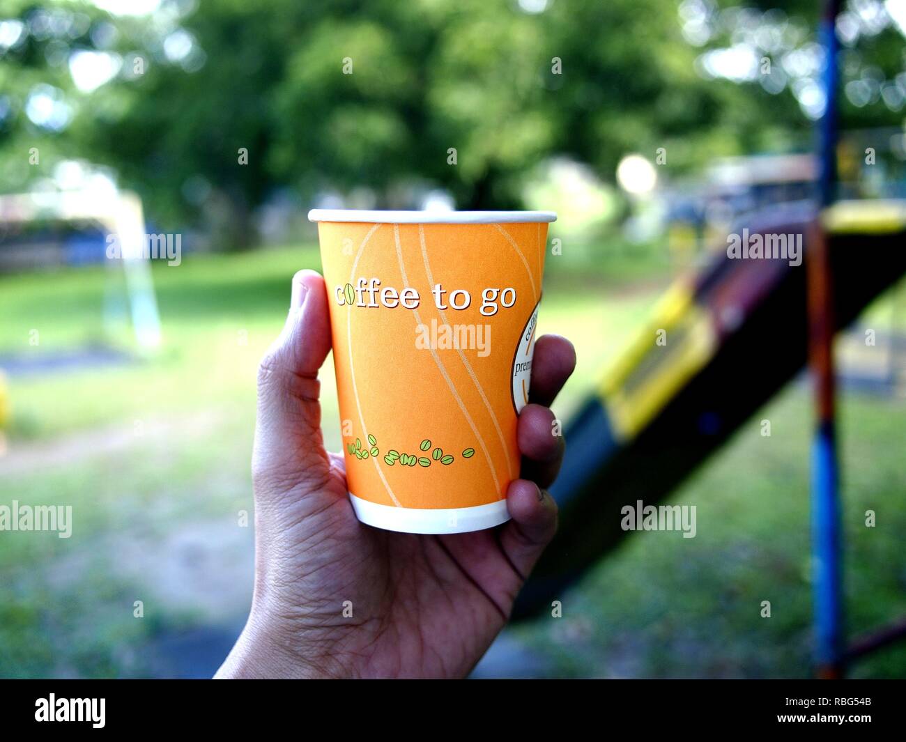 Foto di una mano che tiene un caffè bicchiere di carta a un parco all'aperto Foto Stock