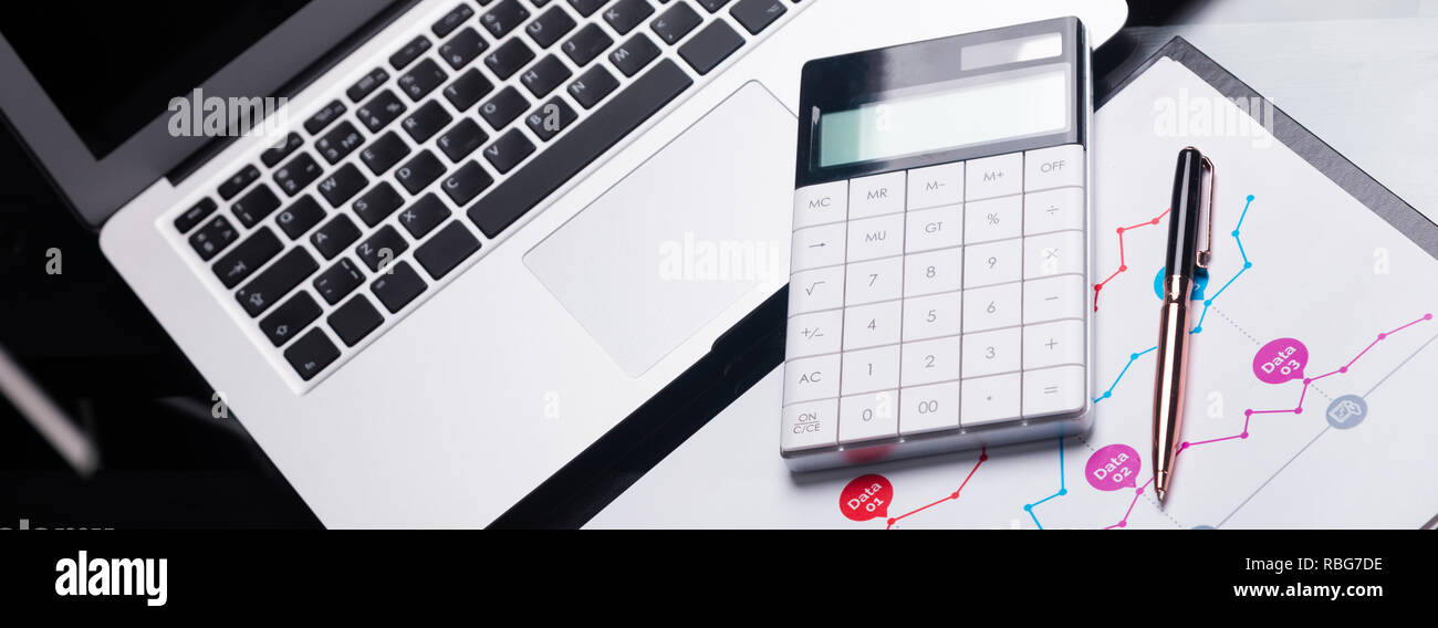 Calcolatrice moderna è su un portatile e su un foglio con un grafico Foto Stock
