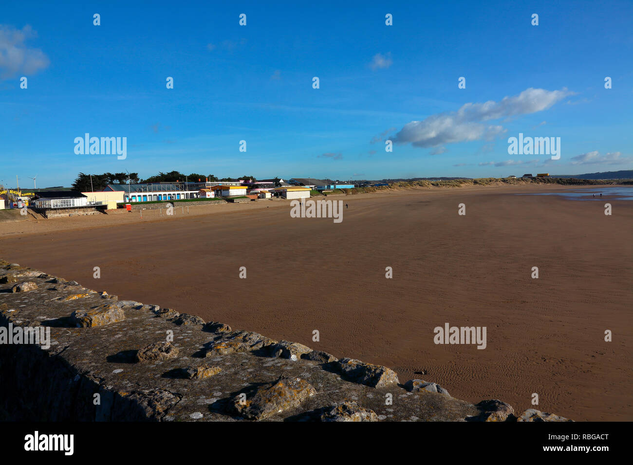 Il Landmark faro bianco in cima al promontorio roccioso a baia di sabbia e trecco bay adiacente a Porthcawl visto attraverso la baia dal lungomare. Foto Stock