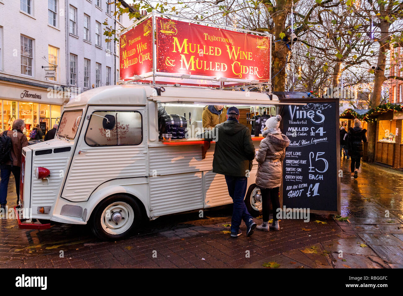 Persone che sono servite bevande calde a vigne vin brulé bar (mobili retrò van servizio catering) a outdoor festoso mercatino di Natale - York, Inghilterra, Regno Unito. Foto Stock