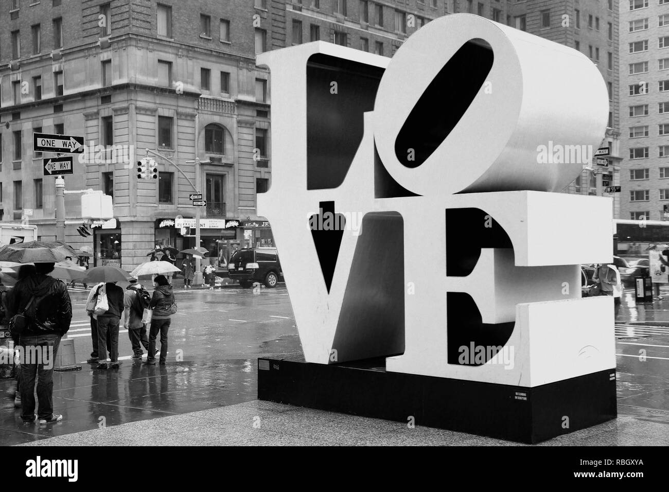 NEW YORK, Stati Uniti d'America - 7 giugno 2013: la gente a piedi passato amore scultura in pioggia nella città di New York. Il famoso monumento da Robert Indiana è situato sulla 6th Avenue Foto Stock