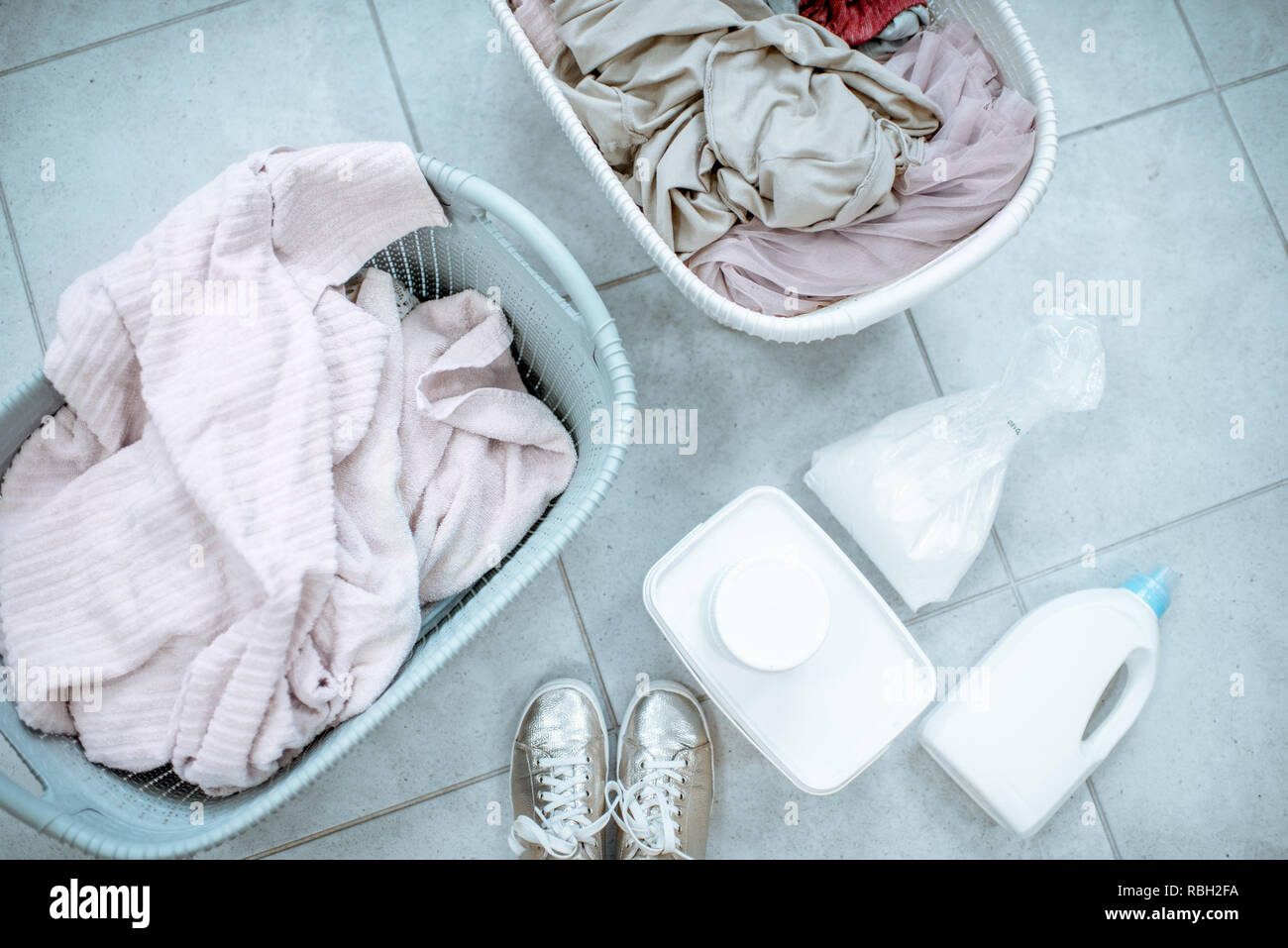 Panni sporchi in cesti con detergenti sul pavimento, vista da sopra Foto Stock