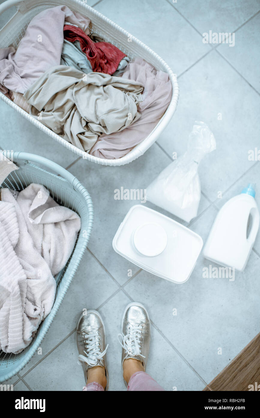 Panni sporchi in cesti con detergenti sul pavimento, vista da sopra Foto Stock