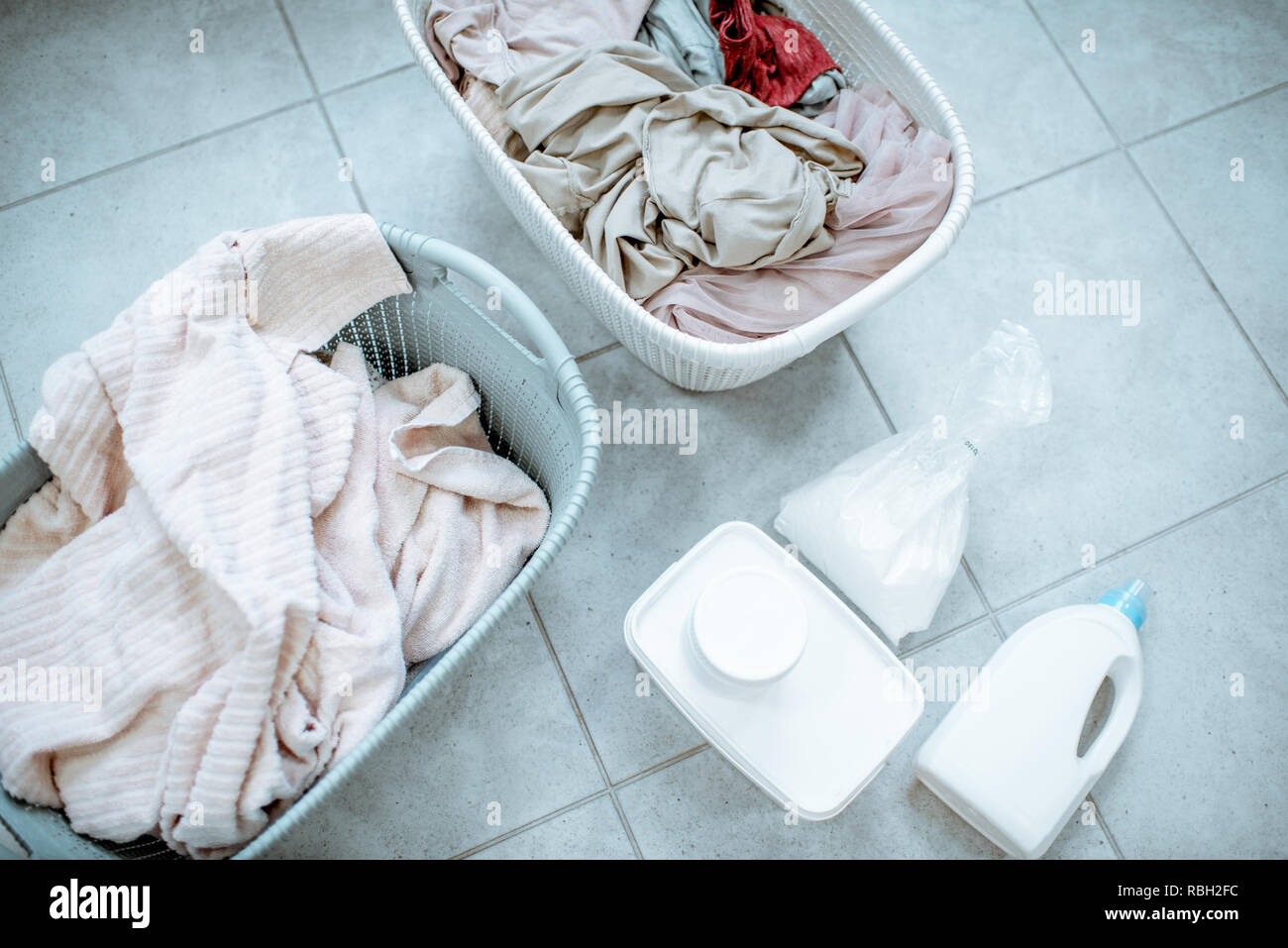 Panni sporchi in cesti con detergenti sul pavimento, vista da sopra Foto Stock