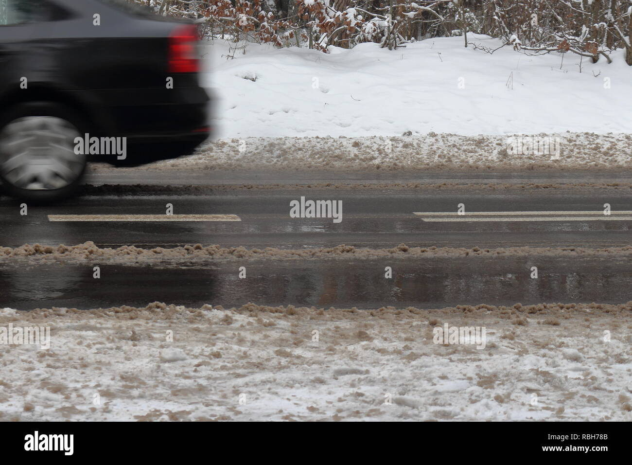 Strada pericolosa per la guida in; ghiacciato, umidi e parzialmente coperto dalla neve Foto Stock