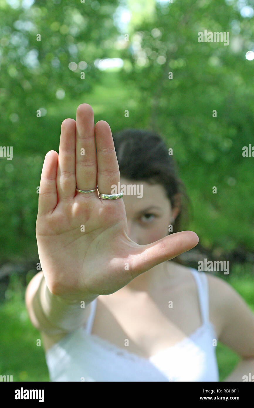 Bruna ragazza in un parco all'aperto in una giornata di sole dando segnali a mano Foto Stock
