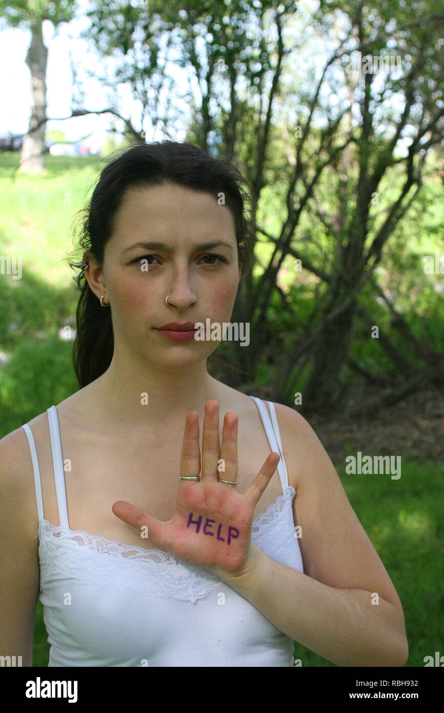 Bruna ragazza in un parco all'aperto in una giornata di sole dando segnali a mano Foto Stock