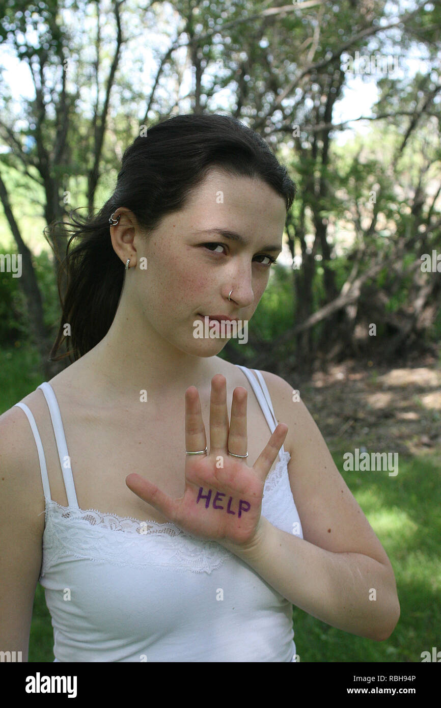 Bruna ragazza in un parco all'aperto in una giornata di sole dando segnali a mano Foto Stock