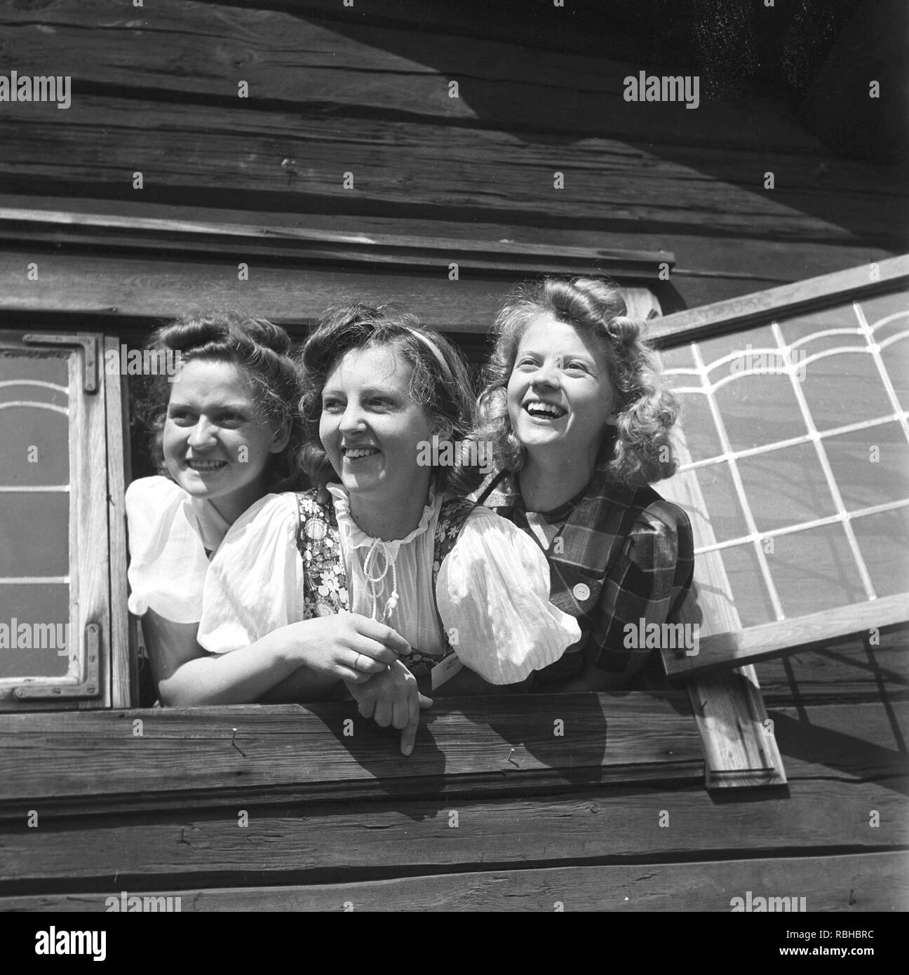 Ragazze in piena estate. Tre giovani ragazze svedesi in costumi tradizionali è appeso fuori da una finestra a un'aria midsummer fiest. Svezia Foto Kristoffersson Ref 219-9. La Svezia 1940s Foto Stock