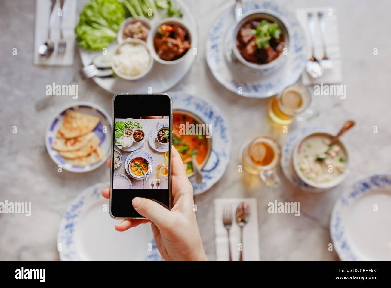 Mano di raccolto a scattare foto di cibo sul tavolo Foto Stock