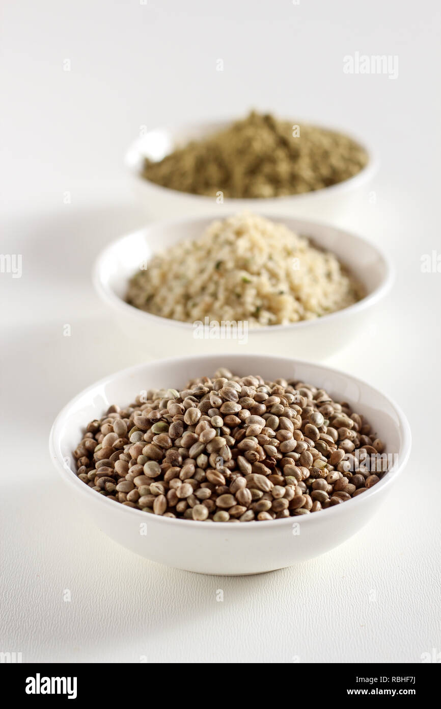 Organico tutta canapa semi, semi mondati e proteine in polvere in ciotole su uno sfondo bianco, verticale Foto Stock