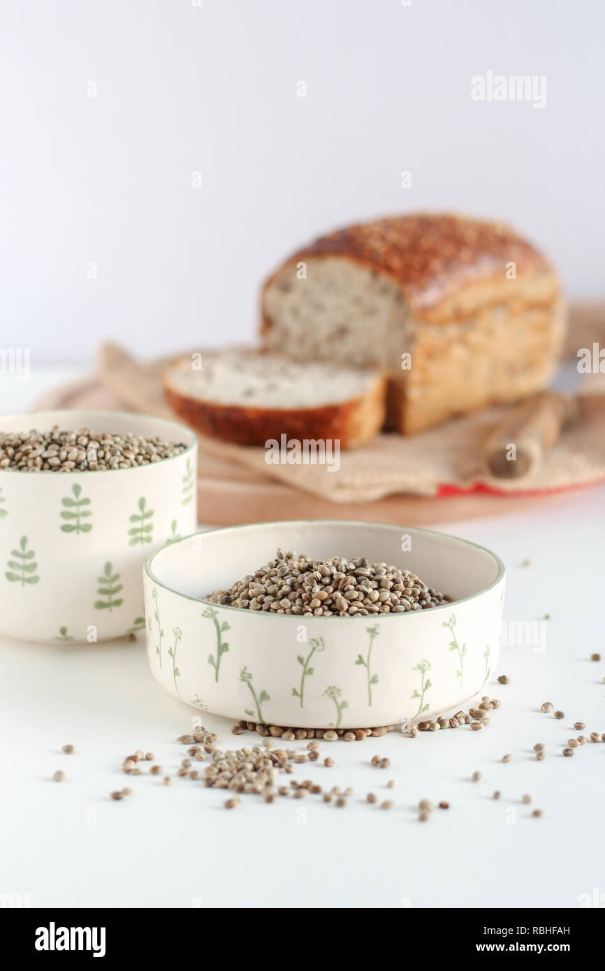 Organico tutta canapa semi in ciotole e pane fatto in casa su sfondo bianco Foto Stock