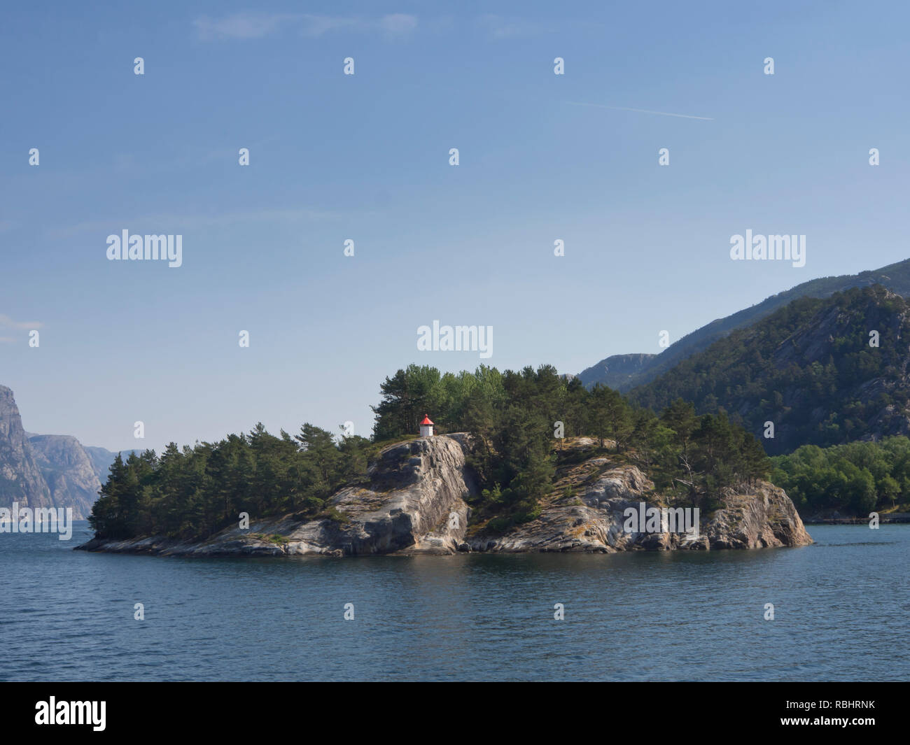 Un giorno di crociera del fiordo Lysefjorden in oriente di Stavanger, Norvegia, piccola isola nel fiordo con un faro e alberi Foto Stock