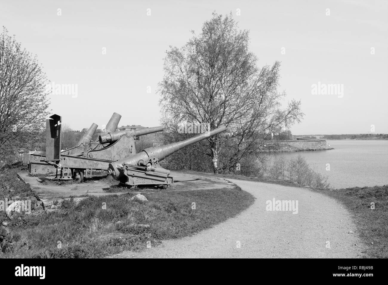 Quattro cannoni arrugginiti dal periodo russo punto sull'acqua dal mare Suomenlinna fortress - elaborazione monocromatica Foto Stock