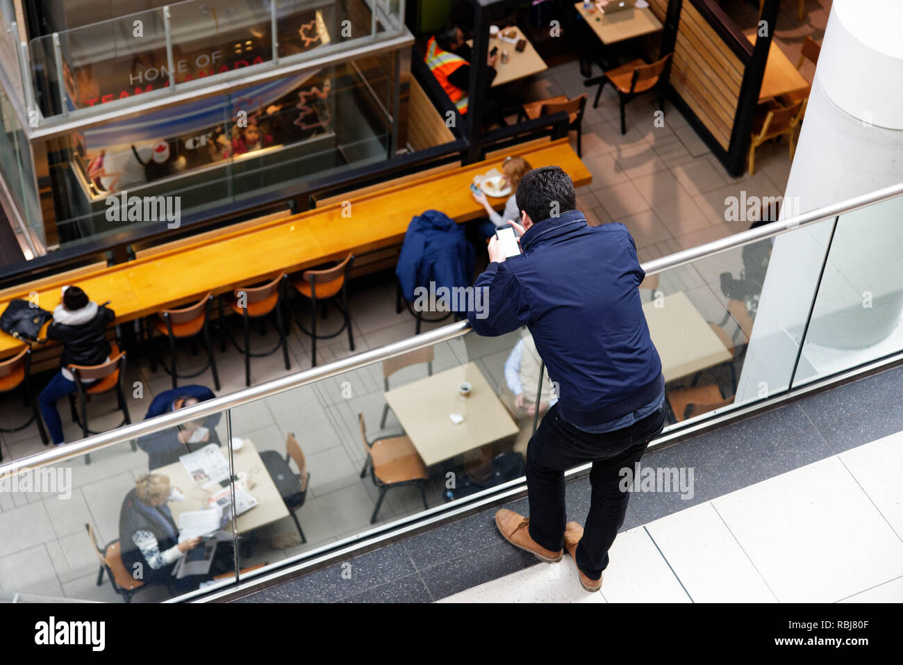 Un uomo con un telefono cellulare in un centro commerciale per lo shopping Foto Stock