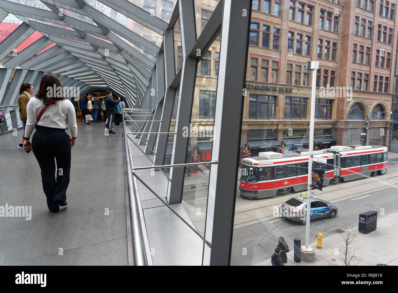 Un traam su Queen Street visto dall'interno dell'elica ponticello del cielo che collega il Centro Eaton per la Baia di Hudson Edificio, Toronto , Canada Foto Stock