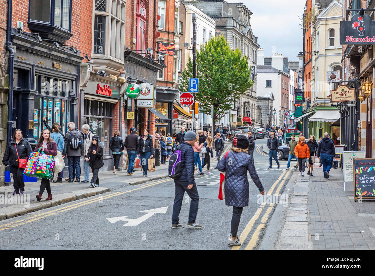 Le persone, le famiglie, i turisti a piedi ed esplorare una trafficata strada commerciale di Dublino, Irlanda. Foto Stock