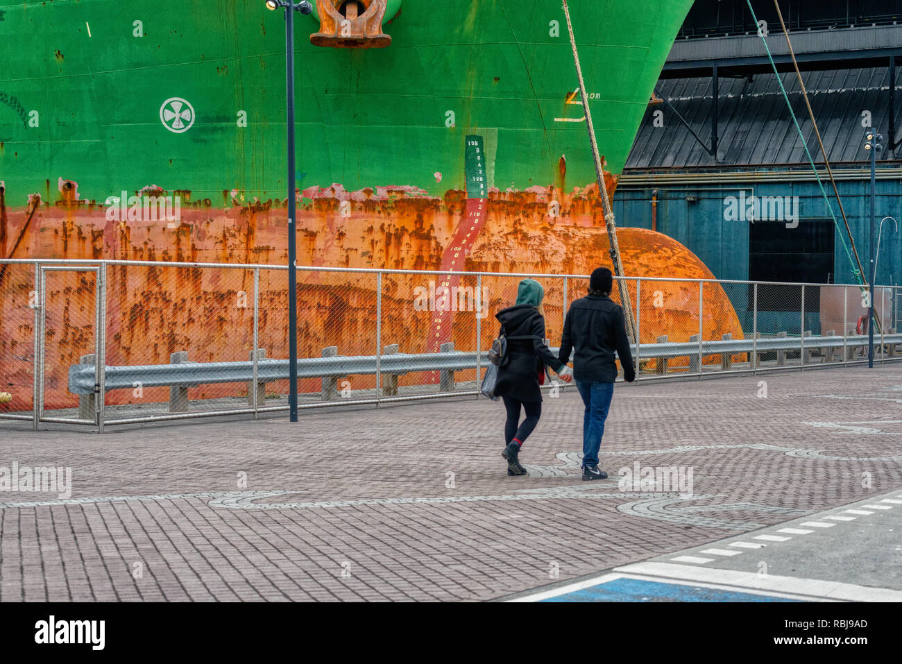 Due pedoni holding hands passando il bulk carrier Wigeon nave nel porto di Toronto, Canada Foto Stock