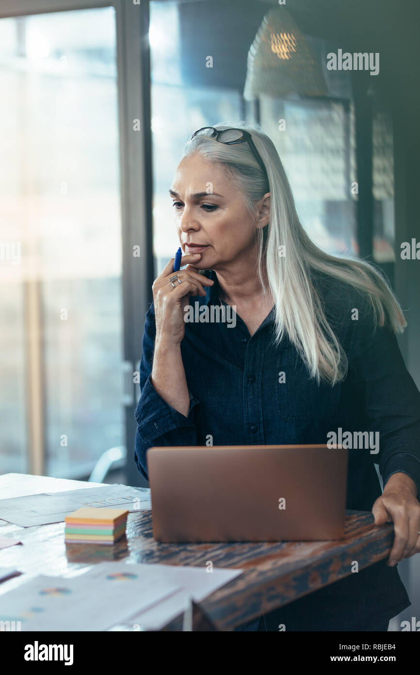 Coppia imprenditrice guardando alcuni documenti e pensando permanente, mentre una tabella di office. Senior business donna che lavorano in ufficio. Foto Stock