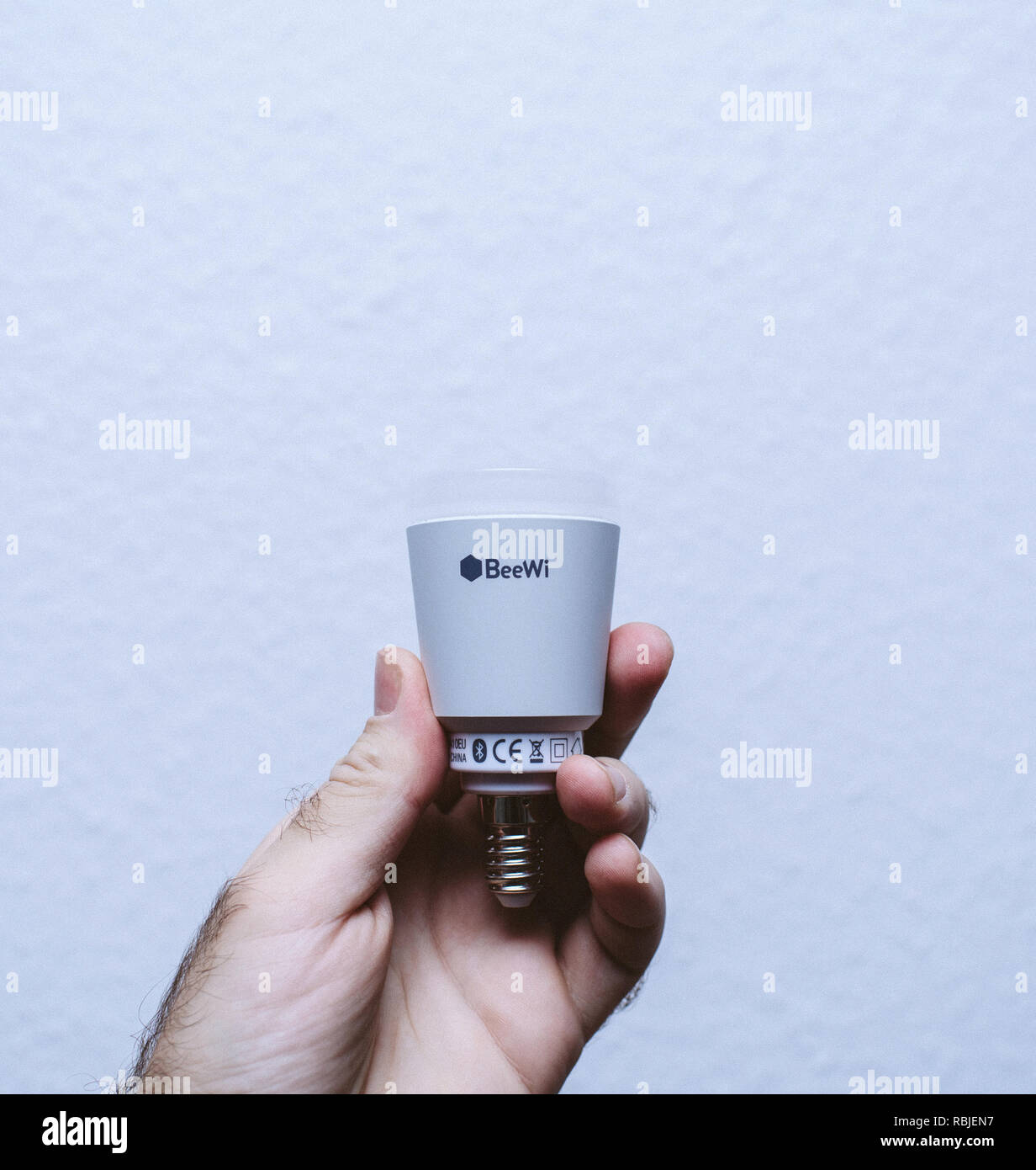 Parigi, Francia - Dic 12, 2017: BeeWi intelligente lampadina della luce nelle mani di uomo contro sfondo blu Foto Stock