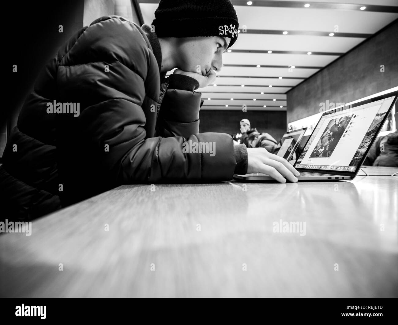 Strasburgo, Francia - 11 GEN 2018: curioso centro-est dell etnia giovane ragazzo utilizzando i più recenti MacBook Pro con retina toccare Bar computer notebook - immagine in bianco e nero Foto Stock