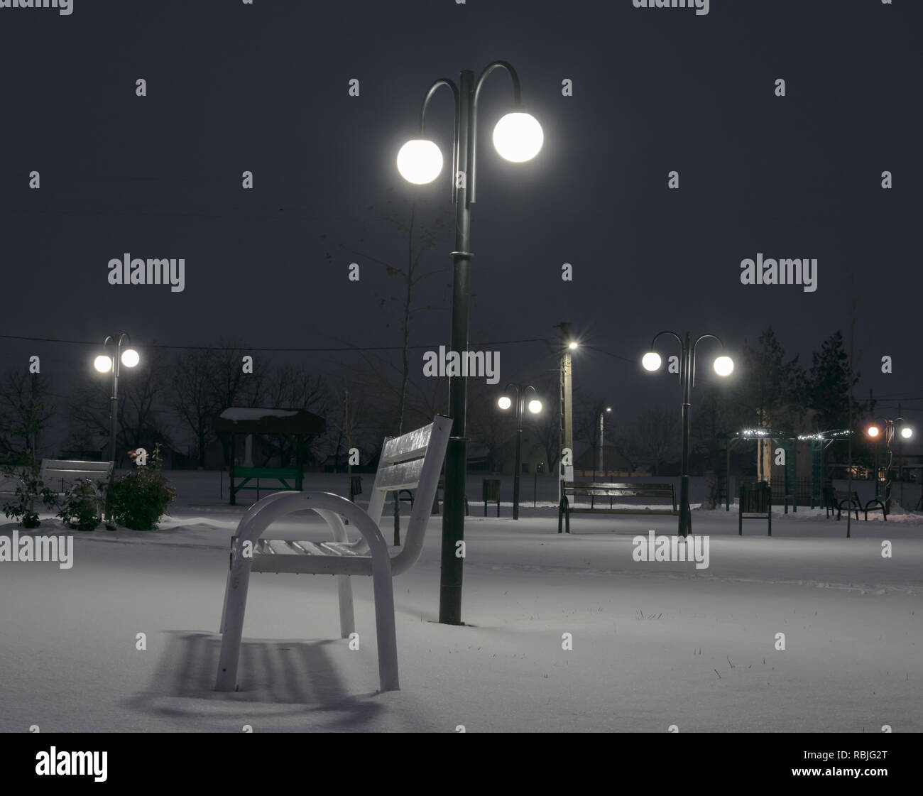 parco di notte in inverno con illuminazione pubblica e panca Foto Stock