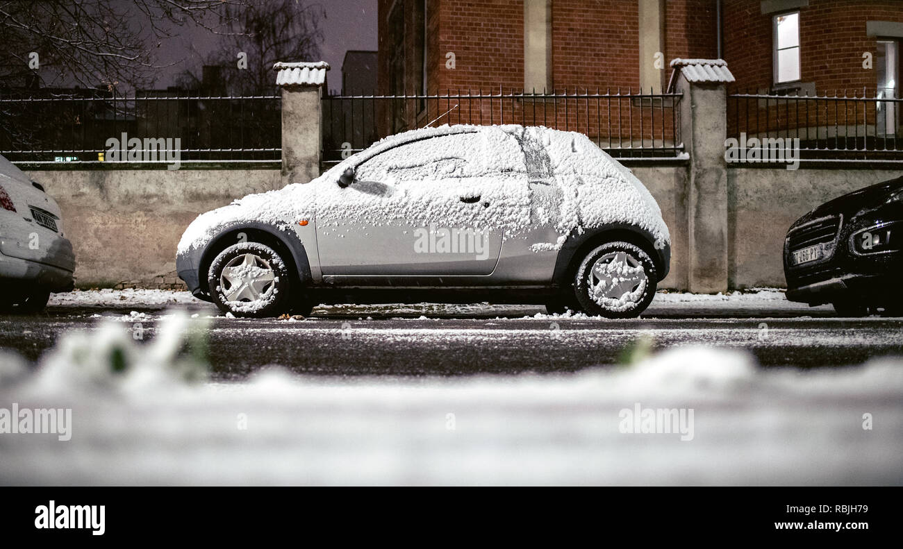 Strasburgo, Francia - 3 dicembre 2017: Ford Ka mini auto parcheggiata su una piccola strada con calma la caduta della neve di notte Foto Stock