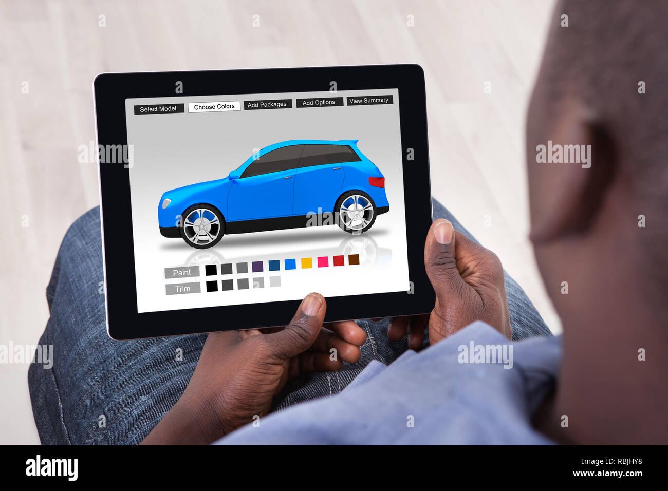 Close-up di un uomo africano la scelta di auto di colore sulla tavoletta digitale Foto Stock