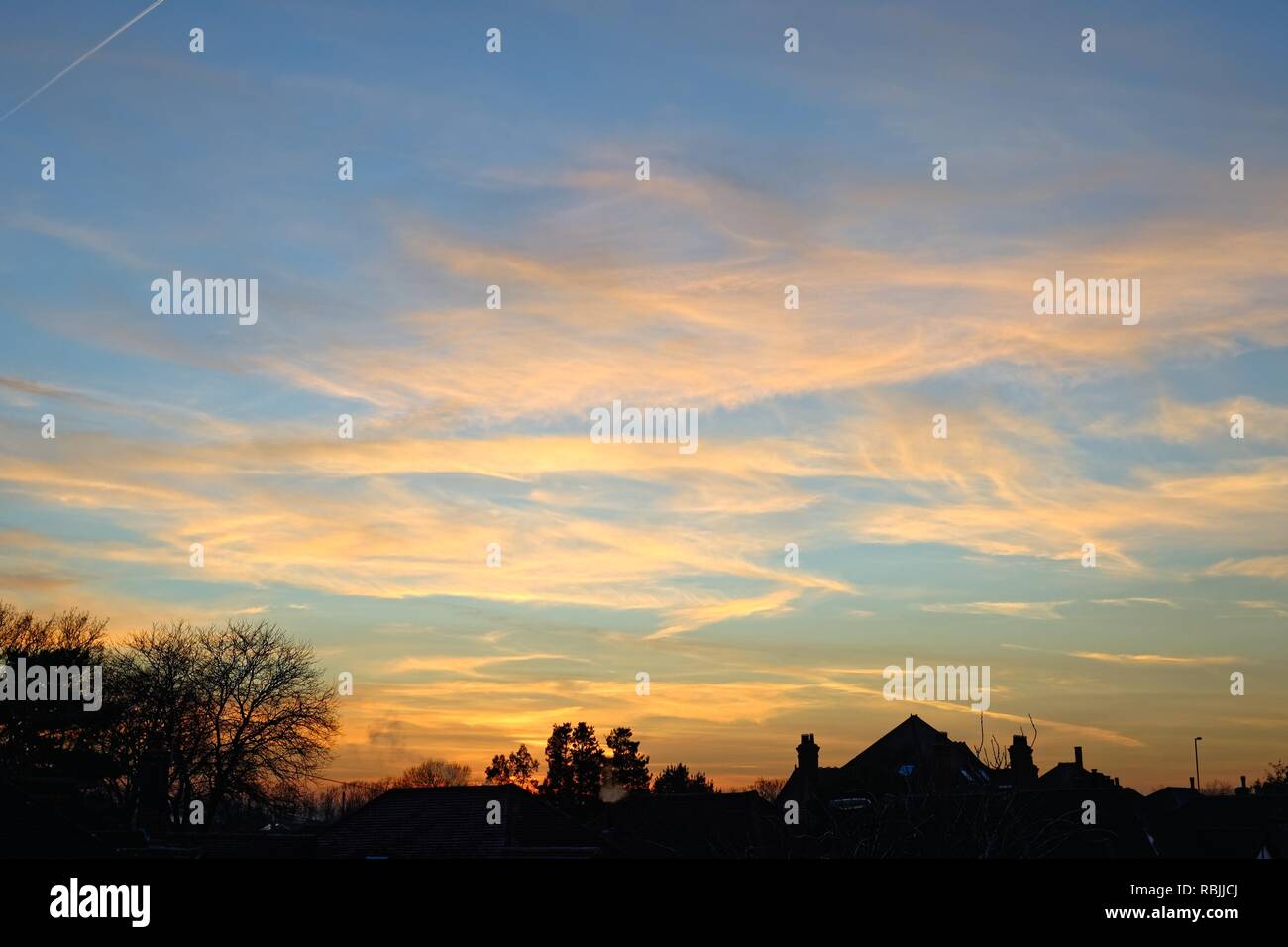 Fumoso tramonto in inverno e nuvole sopra i tetti in Surrey in Inghilterra REGNO UNITO Foto Stock