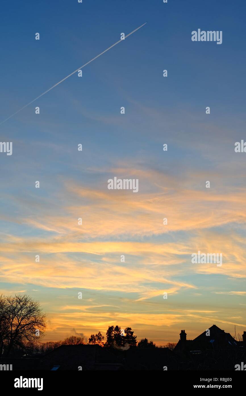 Fumoso tramonto in inverno e nuvole sopra i tetti in Surrey in Inghilterra REGNO UNITO Foto Stock