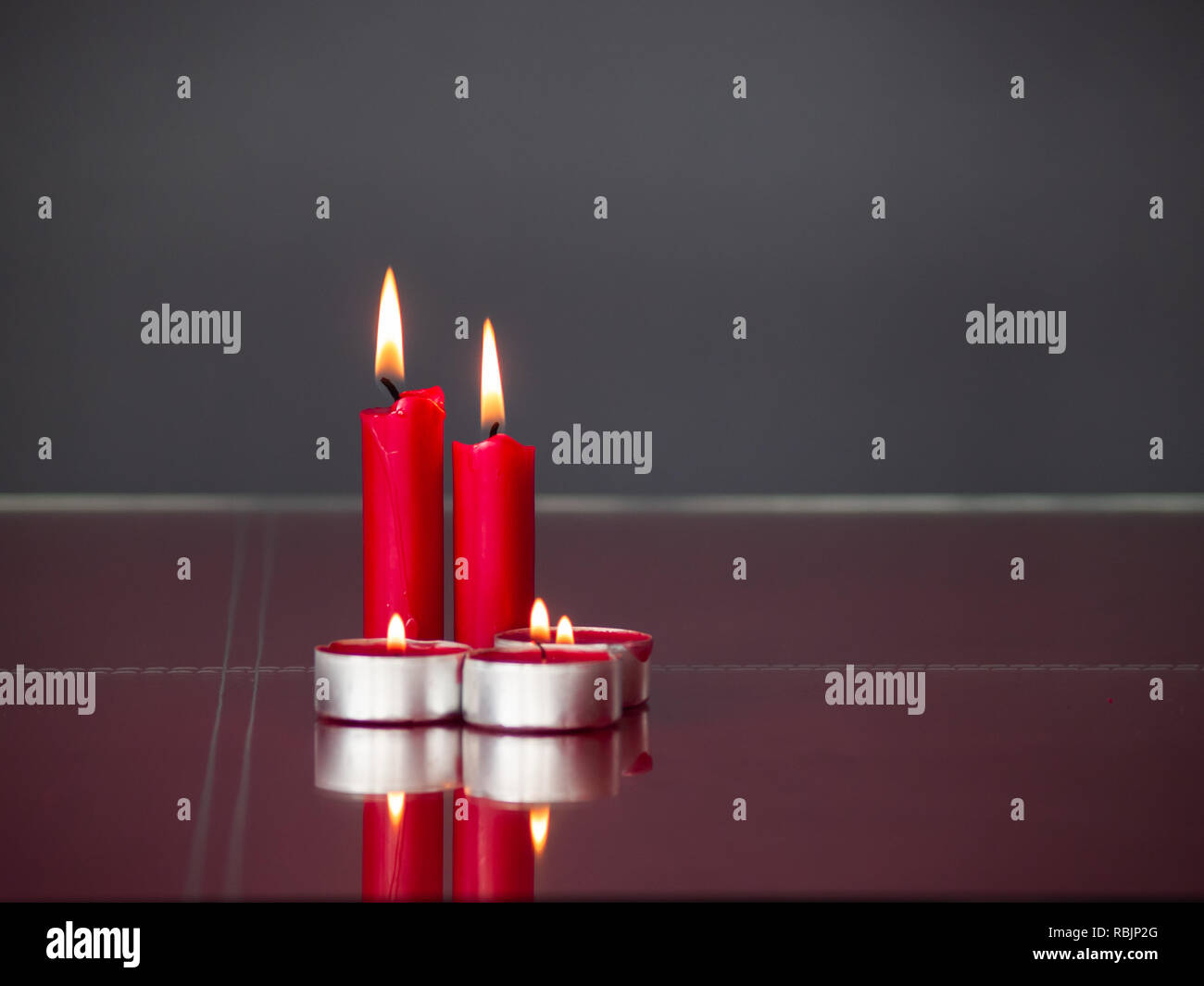 Concetto di amore candele rosse accese con sfondo grigio Foto Stock